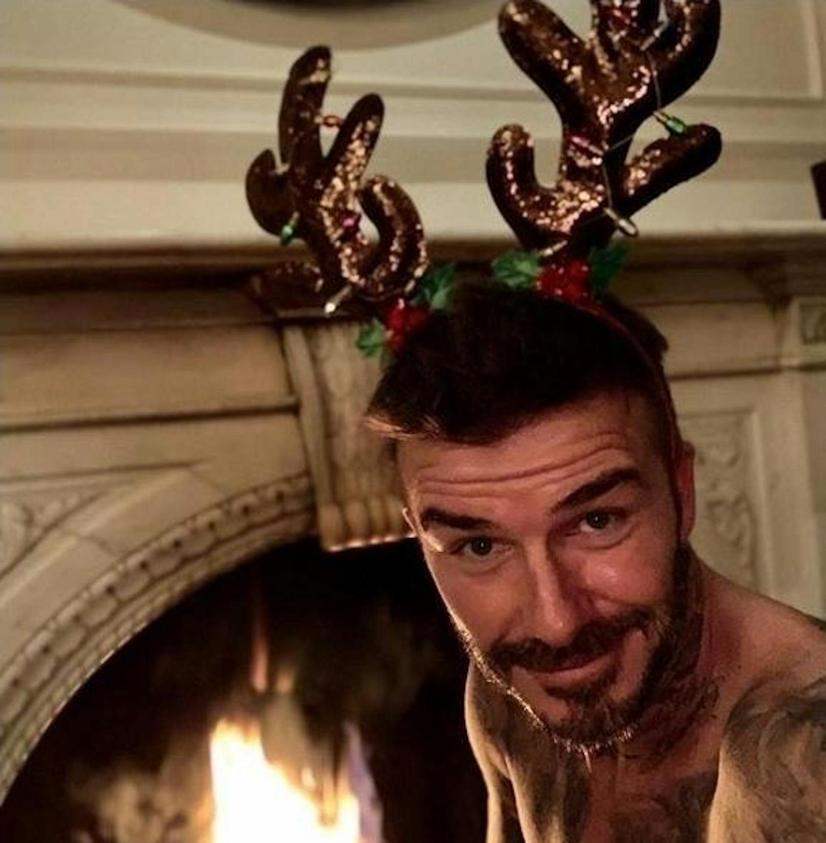 24.12.2018: David Beckham wünscht all seinen Fans ein frohes Weihnachtsfest. Mit nacktem Oberköper. Vor einem brennenden Kamin. Mit Rentiergeweih am Kopf.