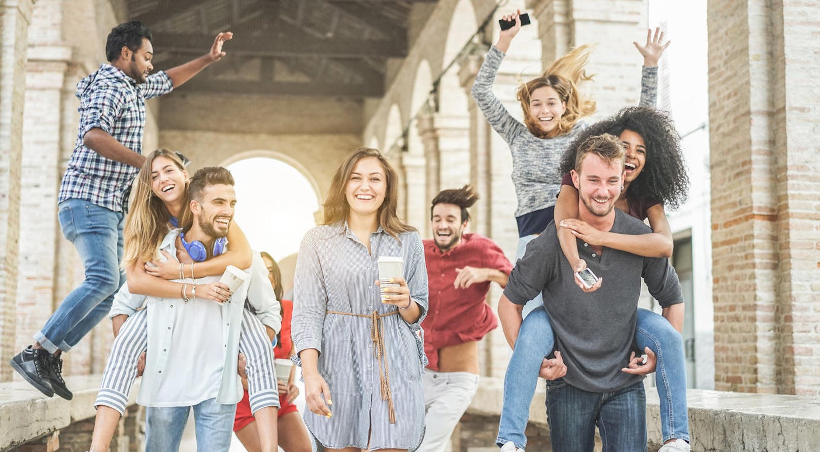 Happy students having fun in old city center - Young people at university break enjoying time together - Youth and positive mood with friends concept - Focus on center woman holding coffee paper cup