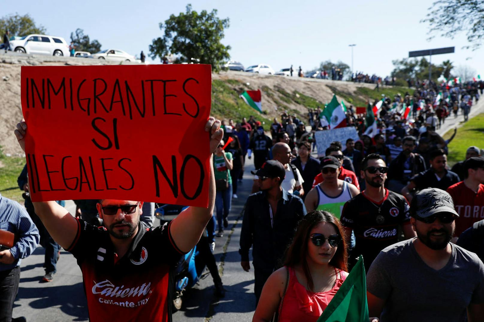 Ein Demonstrant hält ein Transparent hoch, auf dem steht: "Immigranten ja, Illegale nein"
