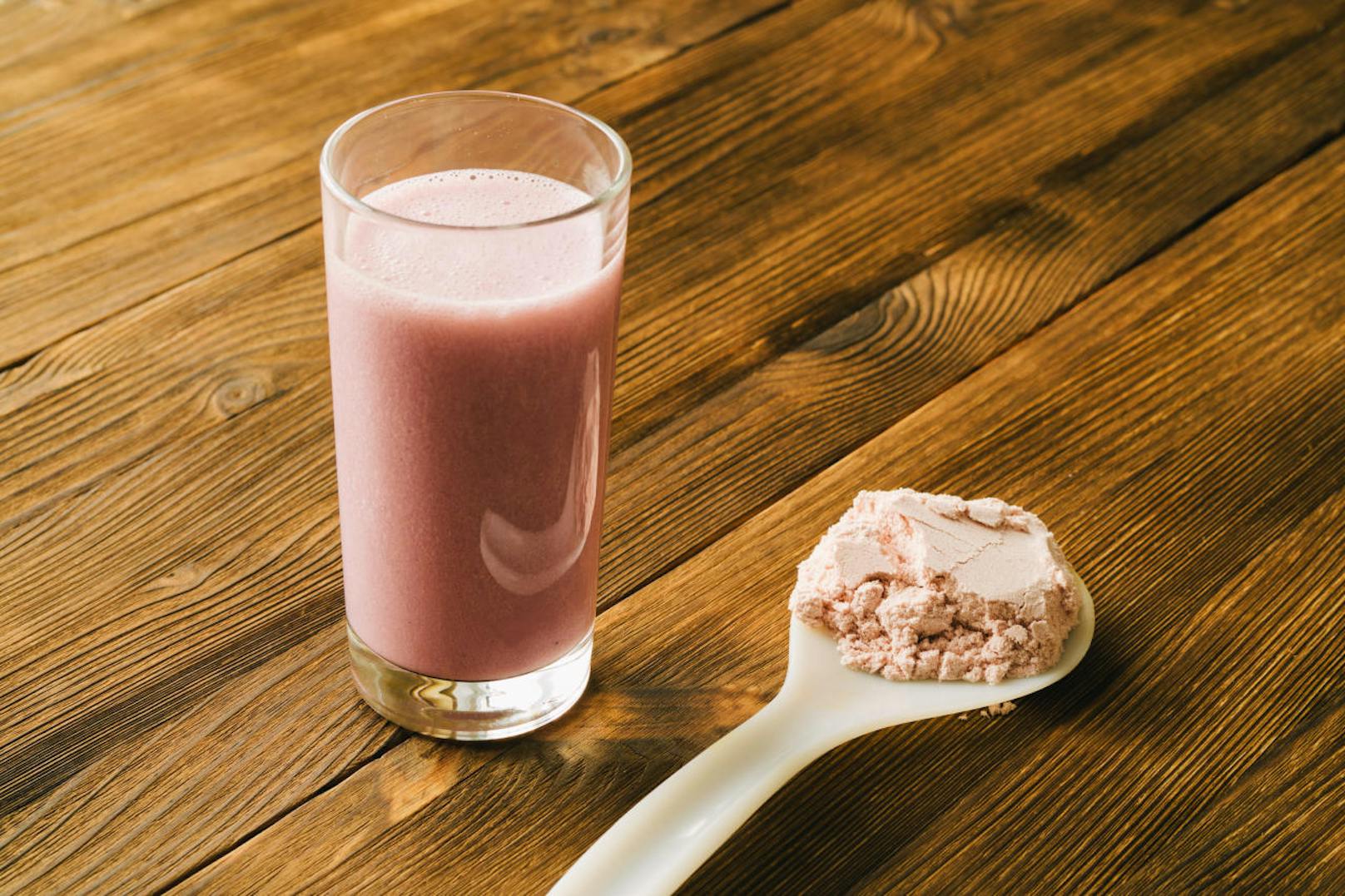 Sports protein on the spoon and in a glass Cup on wooden background