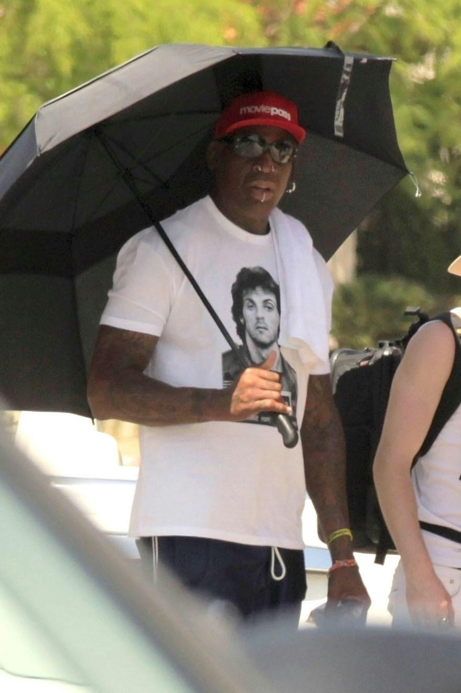 Kim Jong-un: Dennis Rodman setzte sich mit Sly-Stallone-Shirt und Regenschirm in Szene. Ob er den wohl am Eingang abgeben musste?