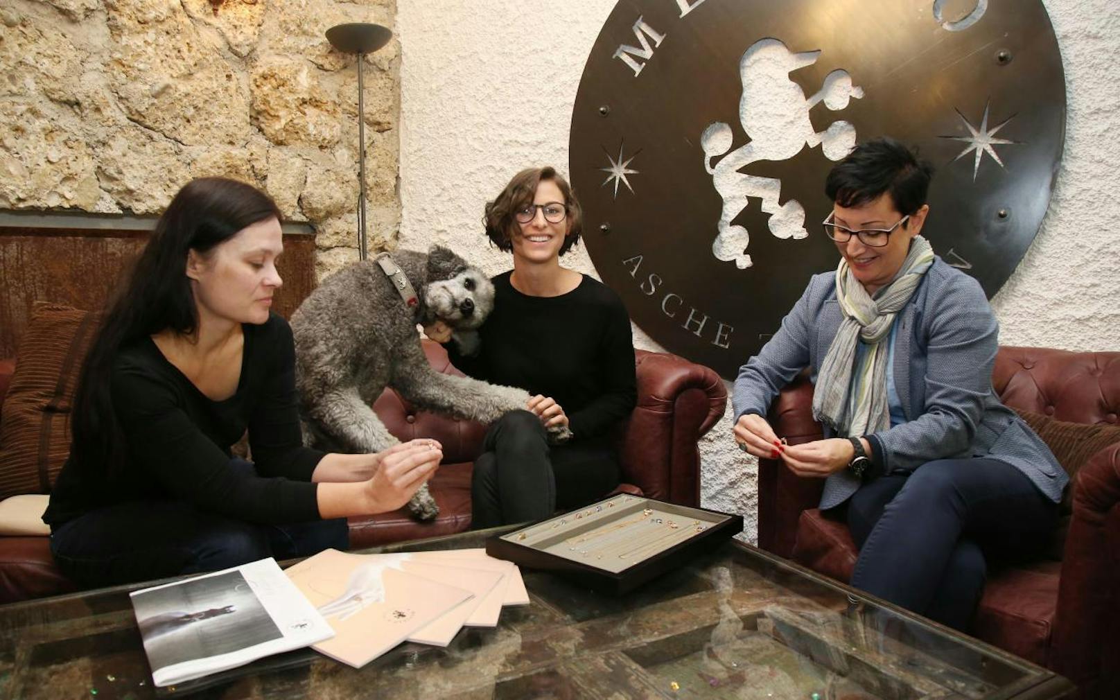 Daniela Reiter von Mevisto (in der Mitte, mit Pudel "Einstein") zeigt "Heute"-Redakteurin Romana Schibany (links) und Simone Strobl (rechts) die verarbeiteten Schmuckstücke.