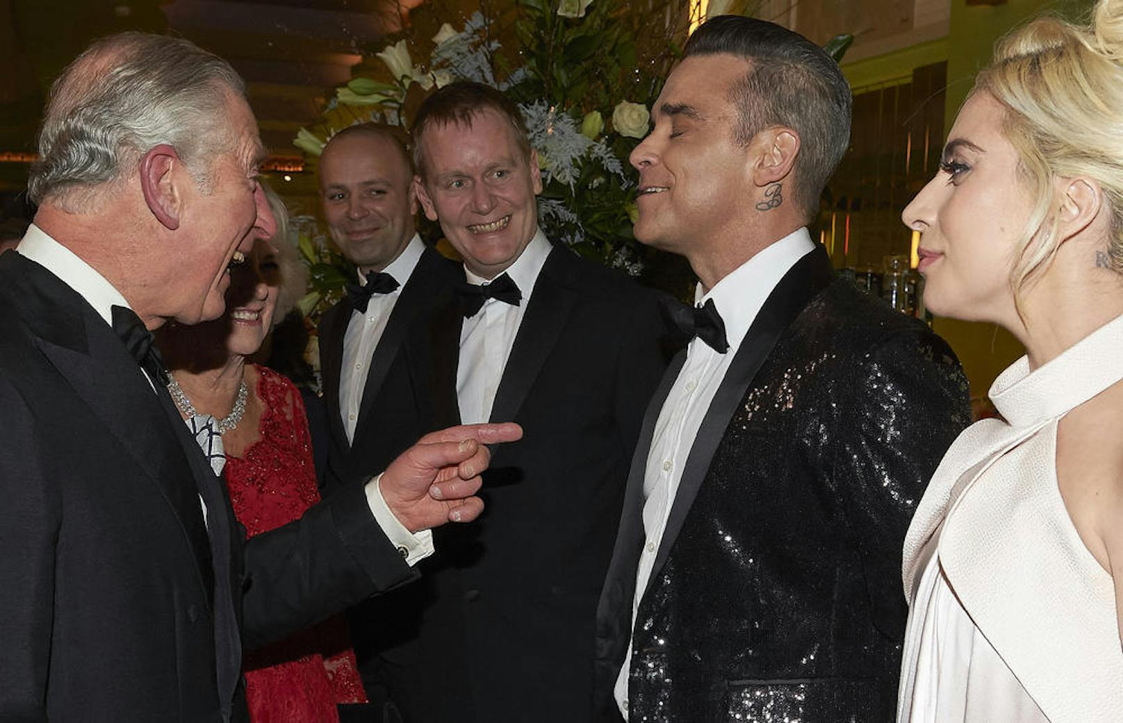 Prinz Charles und Camilla haben Spaß mit Robbie Williams.