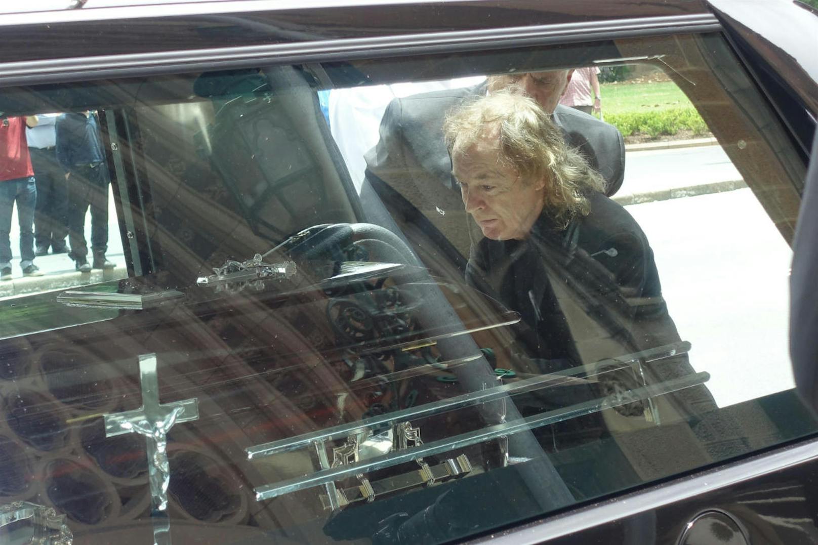 Angus Young vor dem Leichenwagen mit dem Sarg seines Bruders Malcolm.