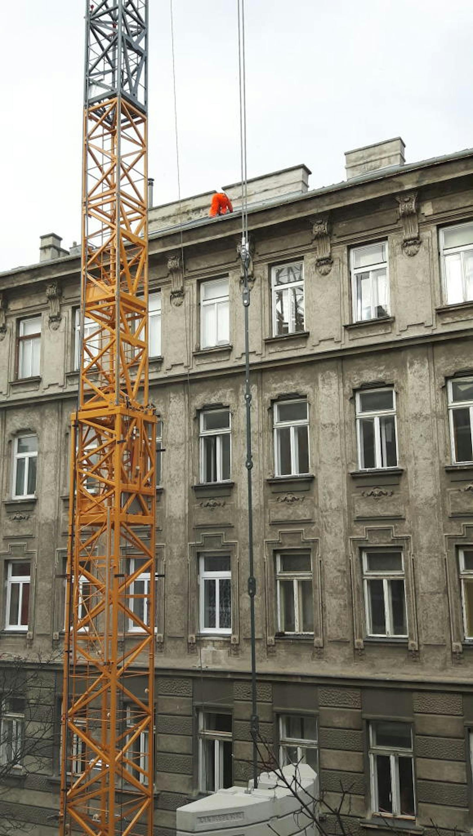 Vollkommen ungesichert arbeitet der Mann in Orange in schwindelerregender Höhe auf dem Dach eines Wiener Wohnhauses.