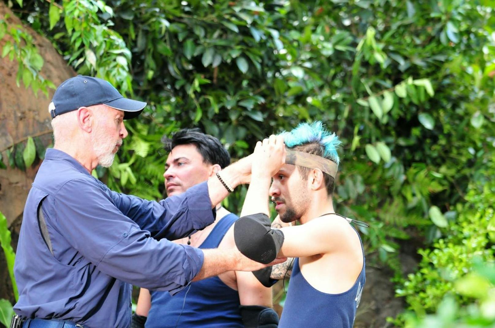 Mit Schutzbrillen, Knie- und Ellenbogenschonern versorgt Dr. Bob (M.) die beiden Dschungelprüfer Matthias Mangiapane und Daniele Negroni (r.).