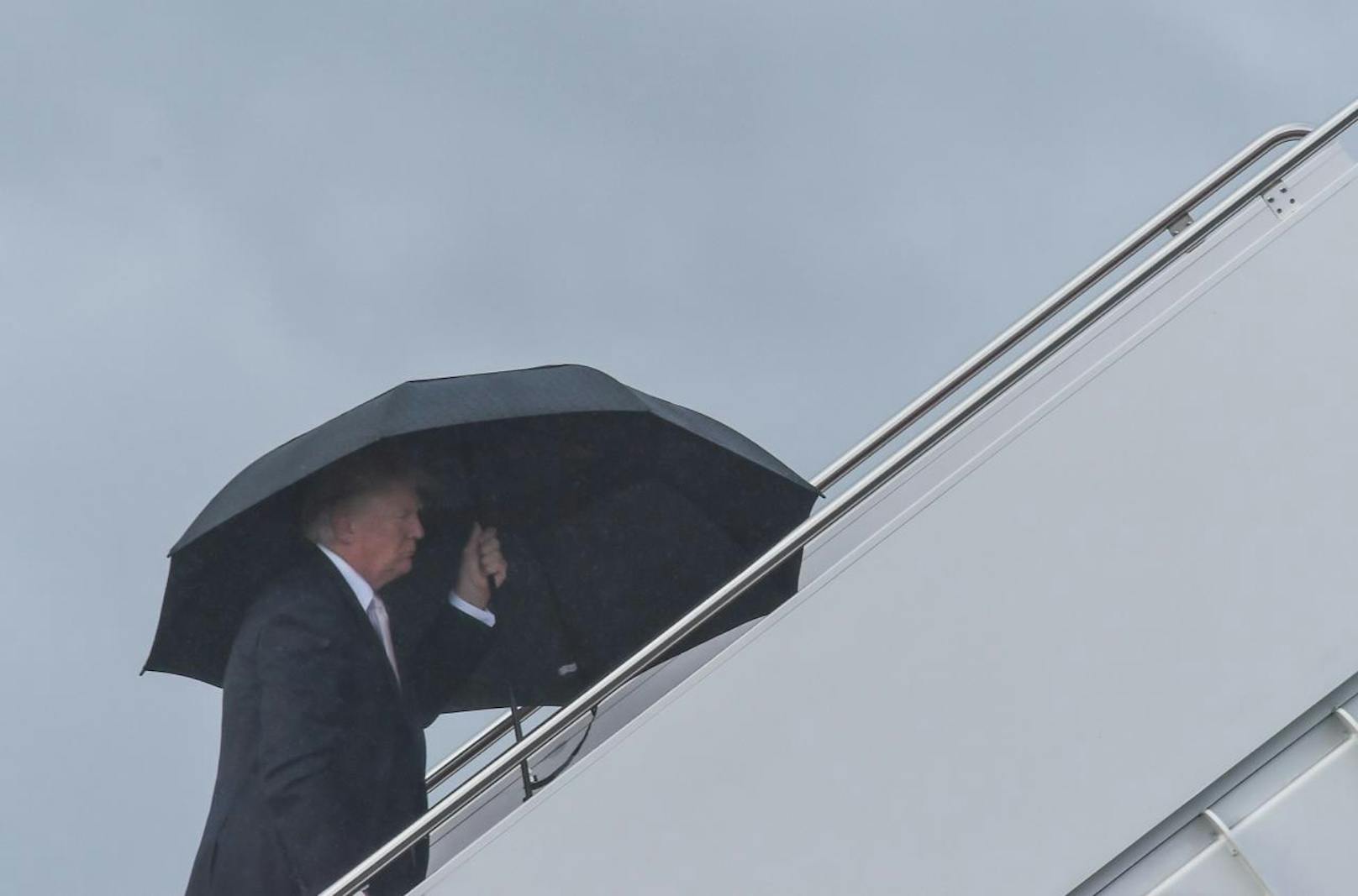 Gut geschützt unter dem Schirm: Präsident Trump besteigt die Air Force One am International Airport in Palm Beach.