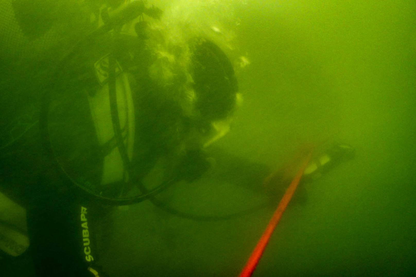 Unter Wasser ist fast nix zu sehen. Die Taucher-Anwärter hängen an einem roten Seil fest.