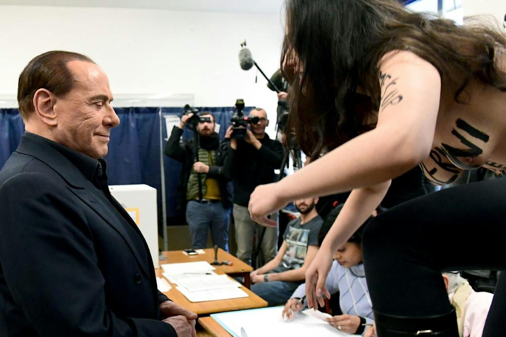 Bei der Stimmabgabe von Silvio Berlusconi, stellte sich ihm ein barbusige Femen-Aktivistin. Der Ex-Premier grinste sein berühmtes Grinsen und wandte sich dann ab.