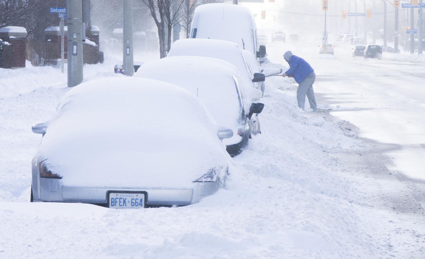 Ein Mann schaufelt in Toronto sein Auto vom Schnee frei.