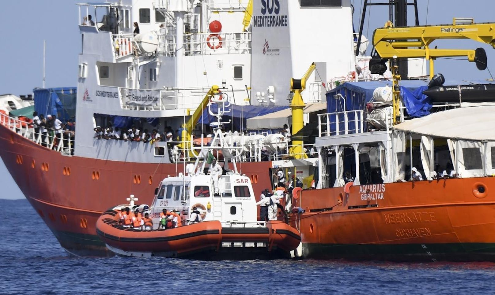 Begleitet wird es dabei von Schiffen der italienischen Marine und Küstenwache, auf welchen ein Großteil der Passagiere temporär Zuflucht gesucht haben.