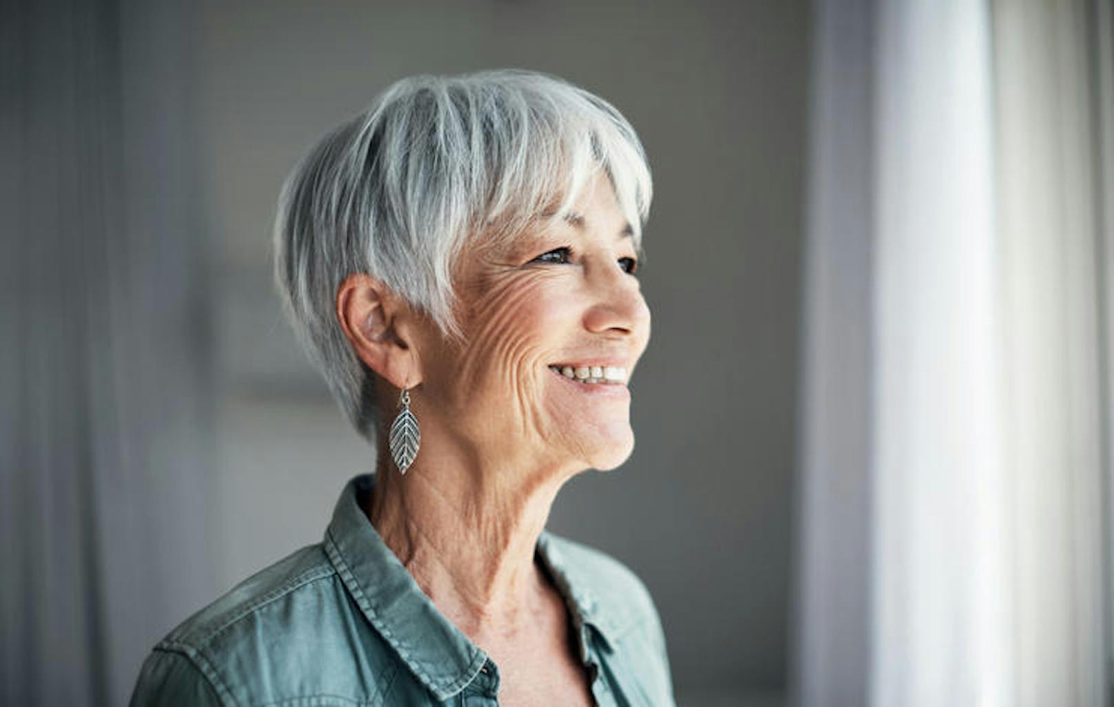 Shot of a happy elderly woman looking out the window at home