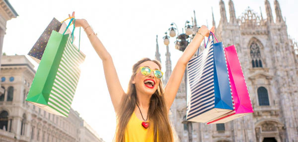 Young woman standing with colorful shopping bags on the main square in front of the famous duomo cathedral in Milan. Happy shopping weekend in Milan