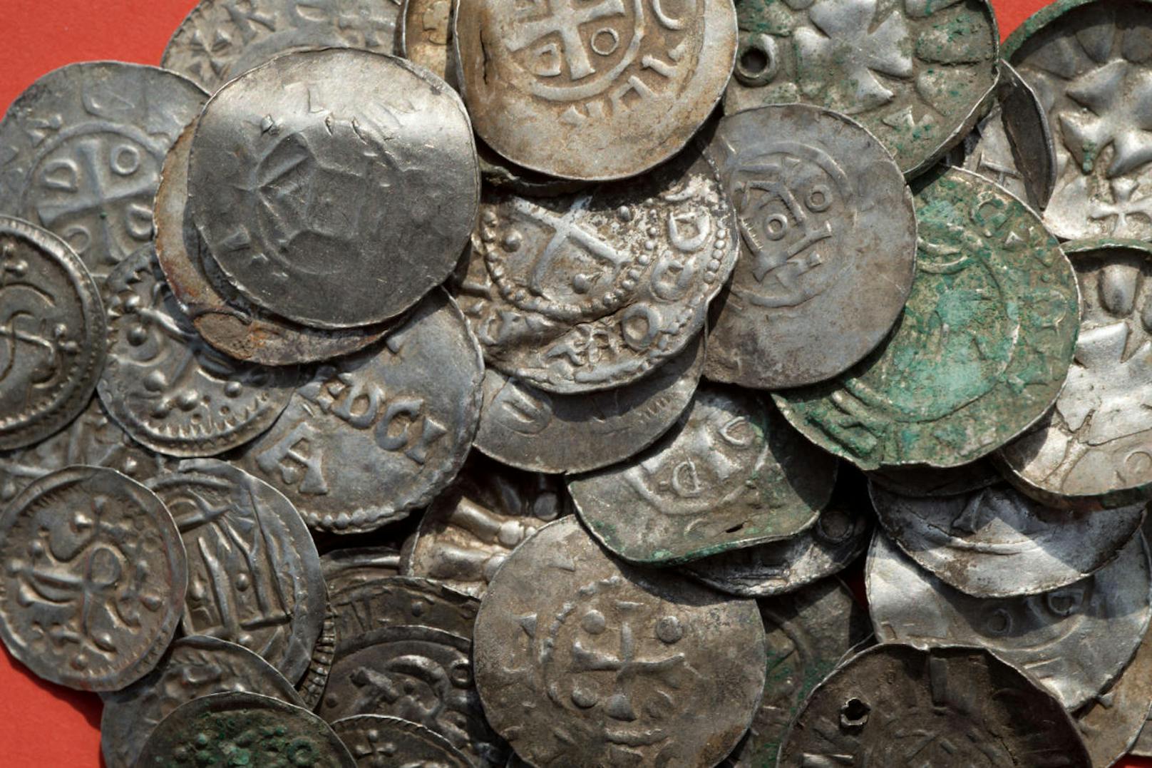 Zusammenstellung von sächsischen, ottonischen, dänischen und byzantinischen Münzen, zum Teil wohl als Anhänger genutzt (durchlocht) liegen auf einem Tisch.