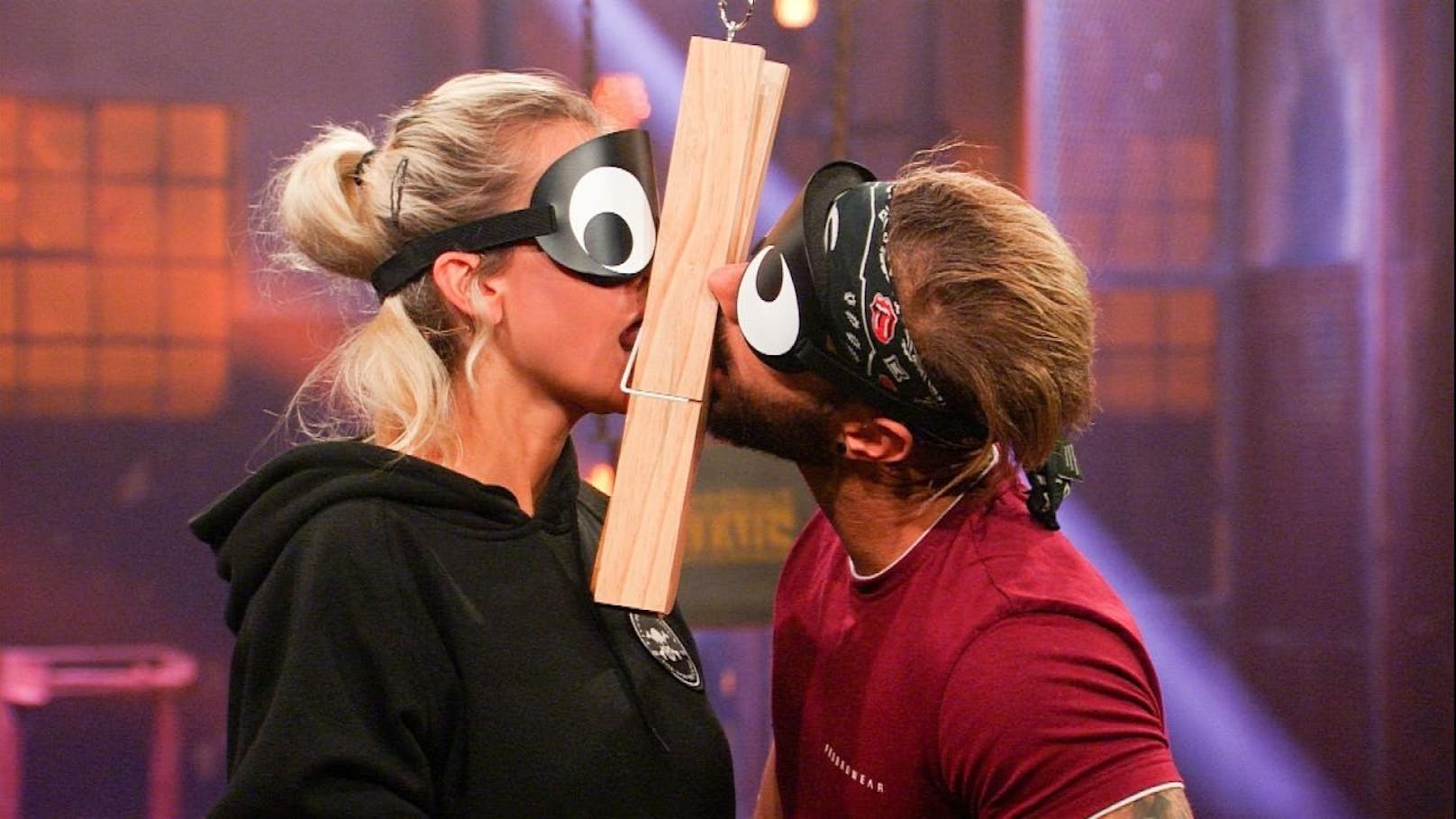 Bei dem Spiel "Das liegt mir auf der Zunge" müssen Stephanie Schmitz und Julian Evangelos blind verschiedene Gegenstände erlecken.