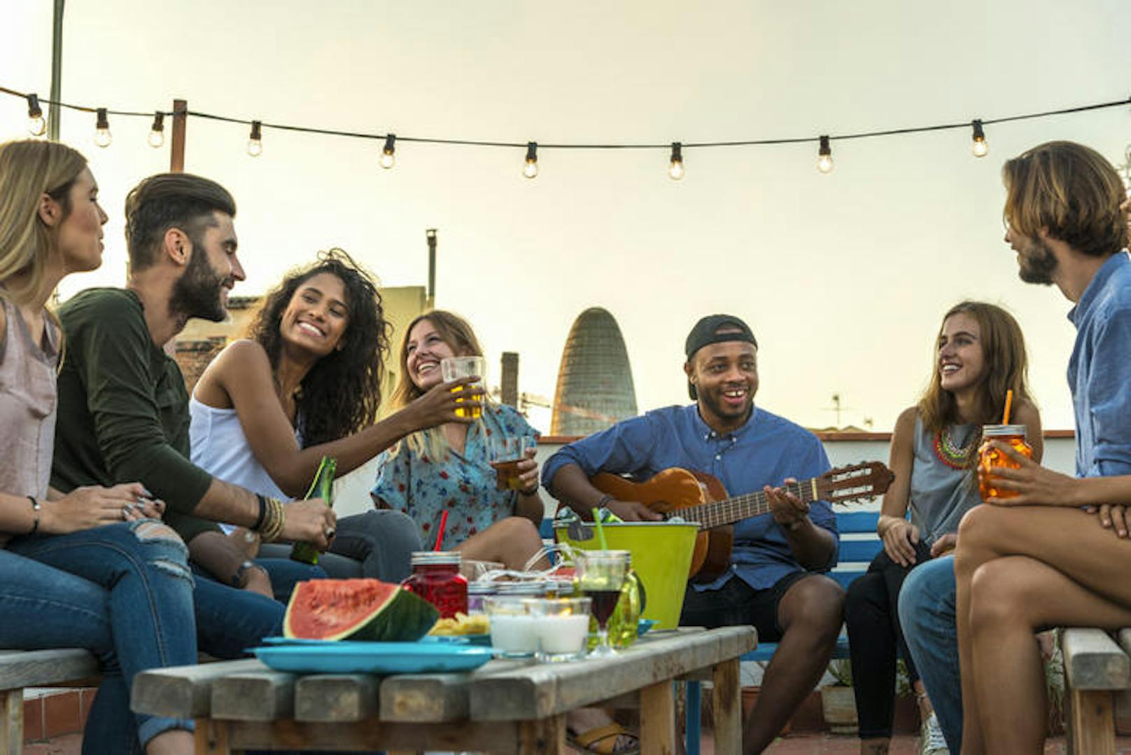 Young adults celebrating life and friendship on a rooftop in Barcelona, Spain. candid shot of eight young friends having fun on a rooftop party