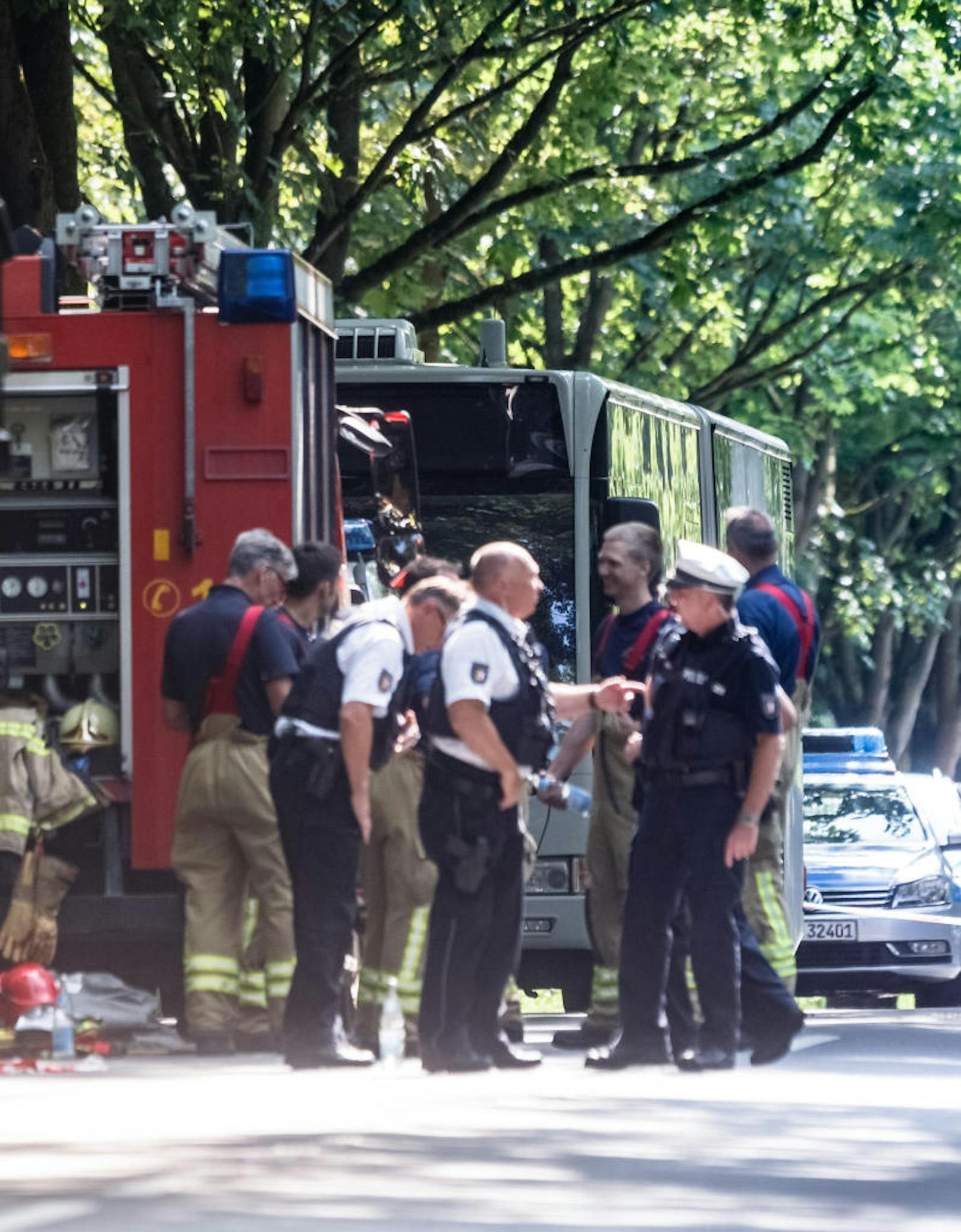 Einsatzkräfte stehen vor einem Bus (im Hintergrund) im Lübecker Stadtteil Kücknitz, in dem am Nachmittag ein Fahrgast Mitreisende mit einem Messer attackiert hatte.