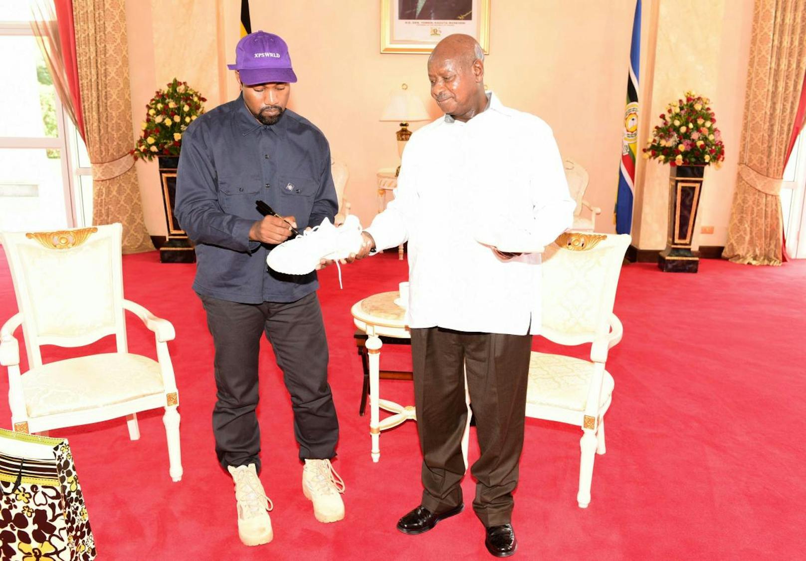 Kanye West signiert einen Schuh für Präsident Yoweri Museveni.