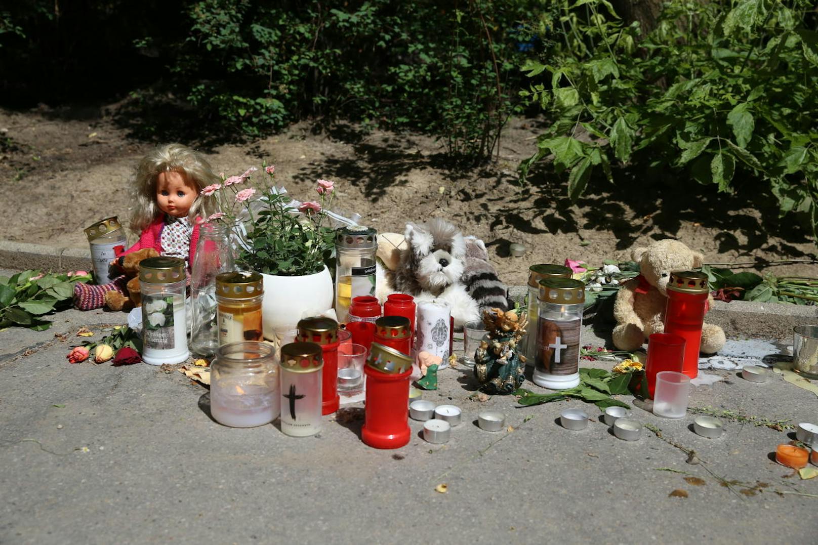 Im Innenhof legen immer mehr Menschen Stofftiere, Puppen und Blumen im Andenken an das ermordete Mädchen ab. Auch Kerzen flackern einsam in Wind.