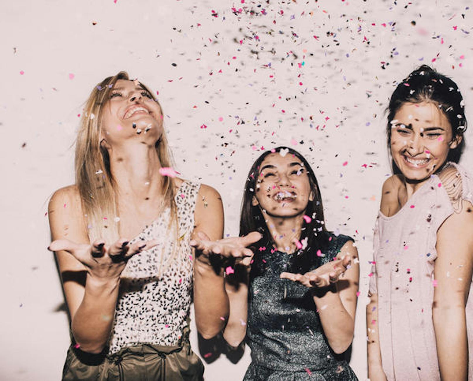 Photo of a group of young women celebrating their youth, femininity  and friendship - tossing a confetti in the air while dancing