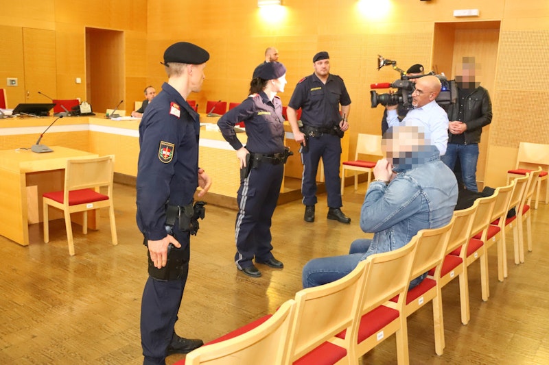 Die beiden Beschuldigten werden von mehreren Polizisten in den Saal gebracht.