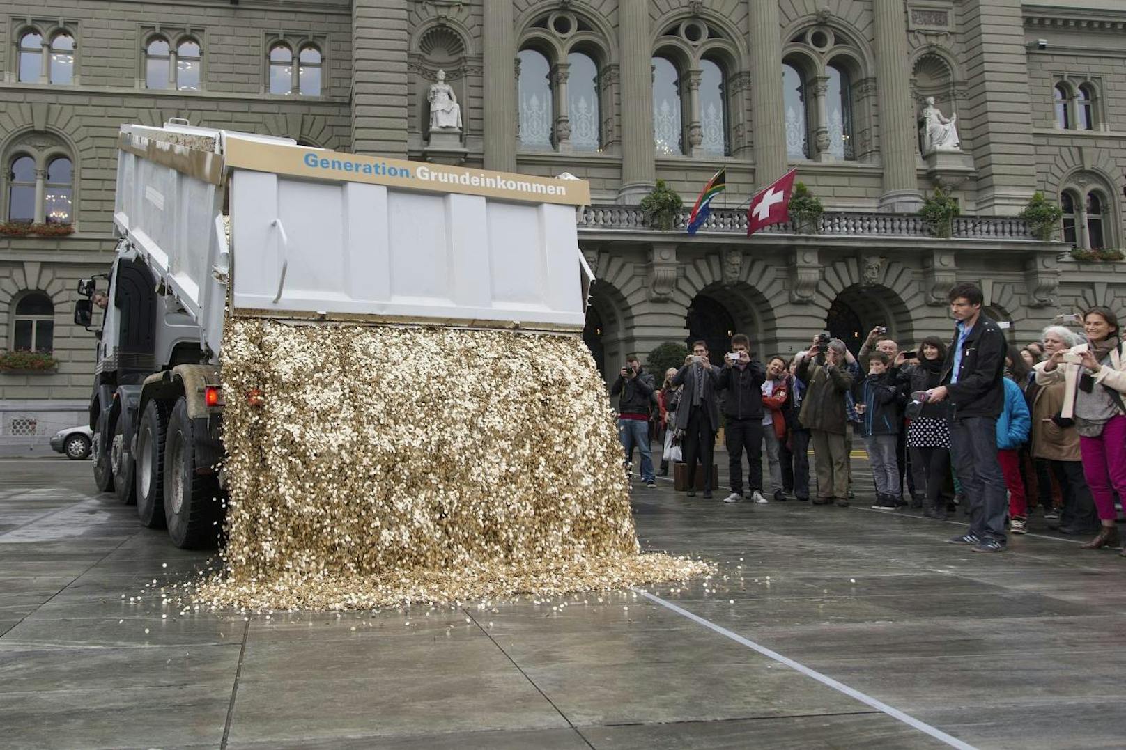 In der Schweiz wurde aus dem Grundeinkommen zwar nichts, die Fotos sind aber zu gut, um sie nicht zu zeigen: Ein Lastwagen kippt eine Ladung von 8 Millionen 5-Rappen-Stücken im Wert von 400.000 Schweizer Franken und mit einem Gewicht von 15 Tonnen auf den Bundesplatz in Bern.
