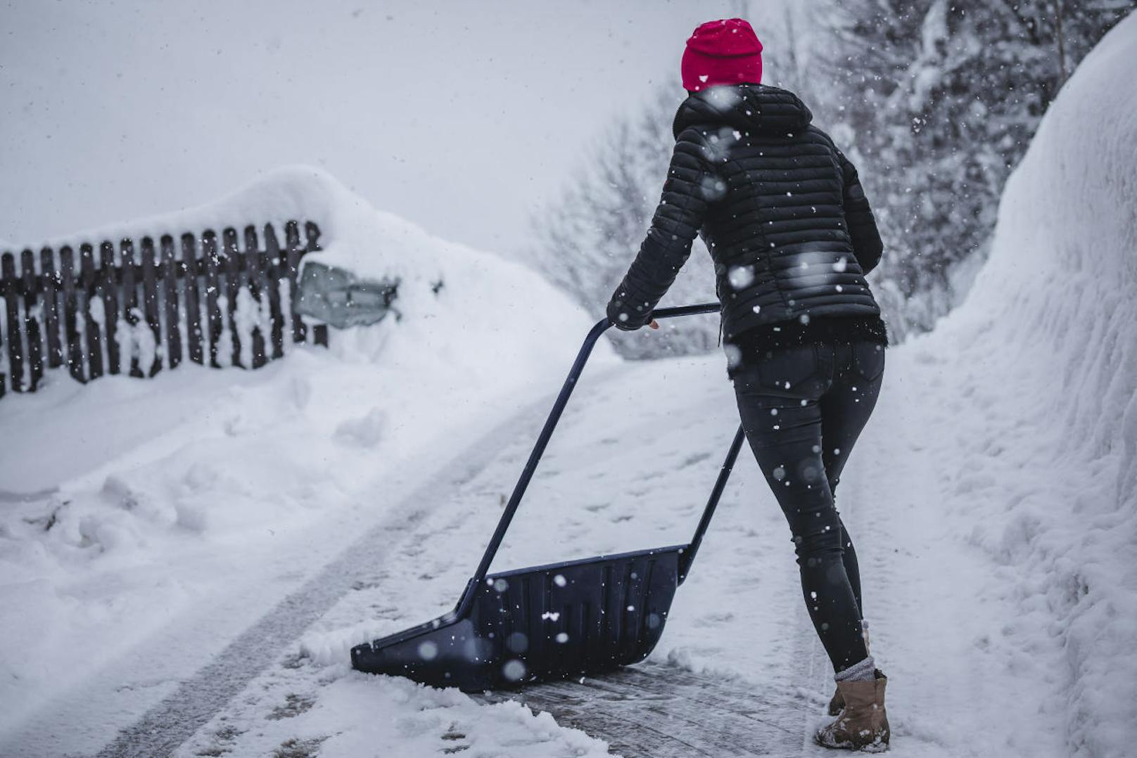 Heftige Schneefälle in weiten Teilen Österreichs: im Bild eine Frau beim Schneeräumen in Saalbach Hinterglemm