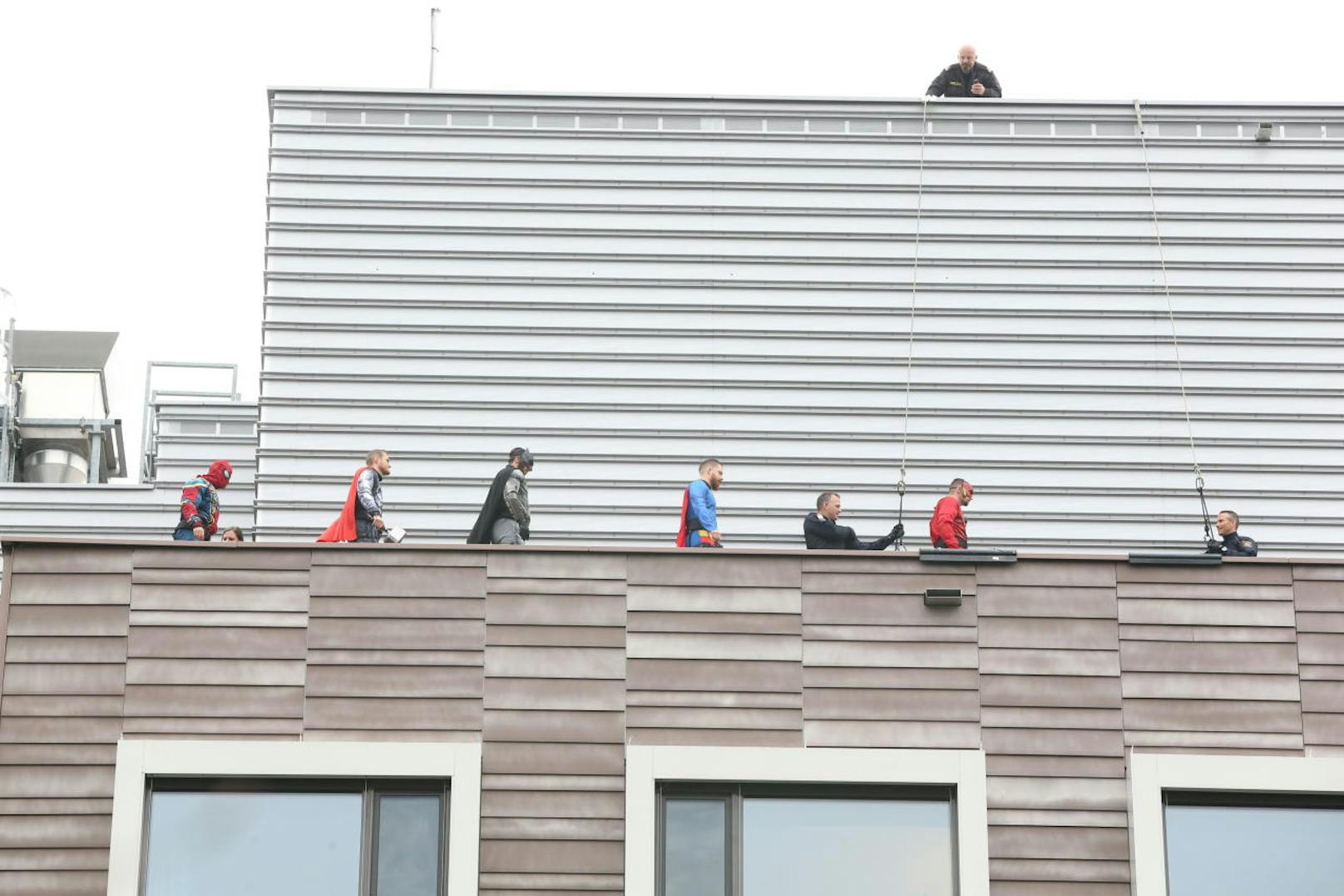 Aufmarsch der Helden: (v.l.n.r.) Spider-Man, Thor, Batman, Superman, Flash beziehen auf dem Dach des Spitals ihre Positionen. Von hier aus seilen sich die Wega-Beamten entlang der Fassade und vorbei an den wartenden Kindern ab.