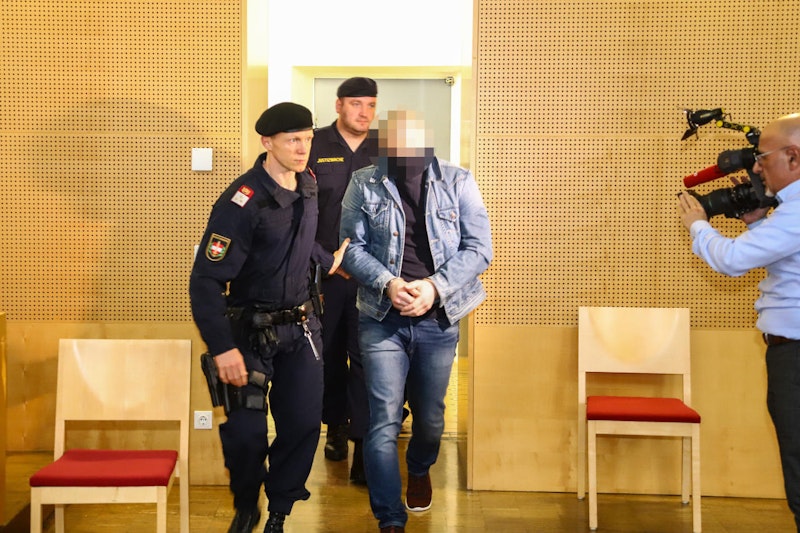 Die beiden Beschuldigten werden von mehreren Polizisten in den Saal gebracht.