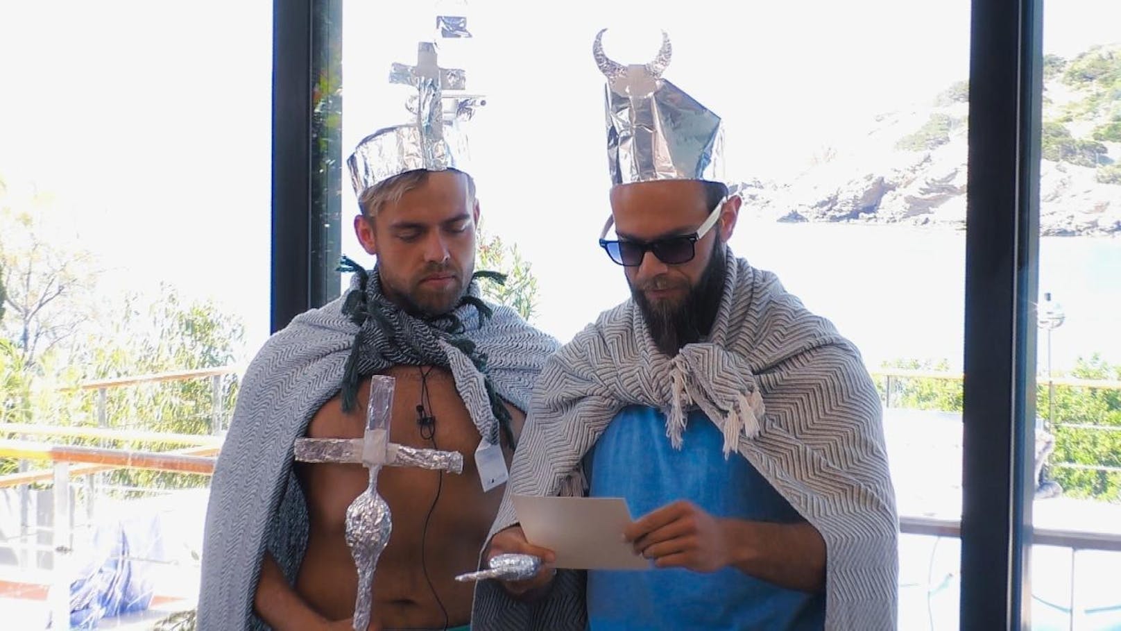 Andreas und Oggy lesen die Nachricht der Bachelorette in einem selbstkreeirten König-Outfit vor. 