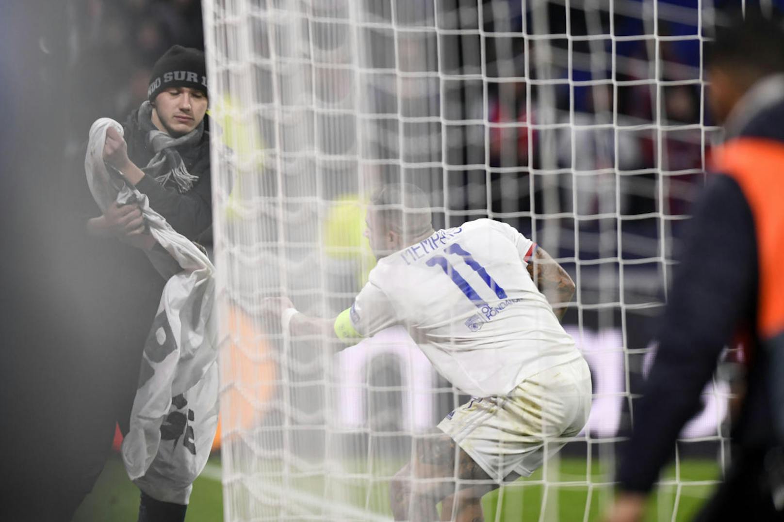 Memphis Depay entreißt den eigenen Ultras das beleidigende Plakat gegen Lyon-Mitspieler Marcelo. Der wehrt sich, zeigt ihnen den Mittelfinger.