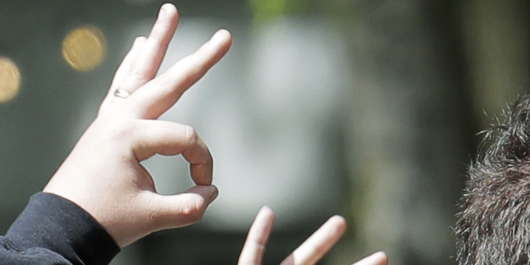 Die drei Finger formen ein "W", der Kreis aus Daumen und Zeigefinger soll ein "P" formen. "WP" steht für "White Power"