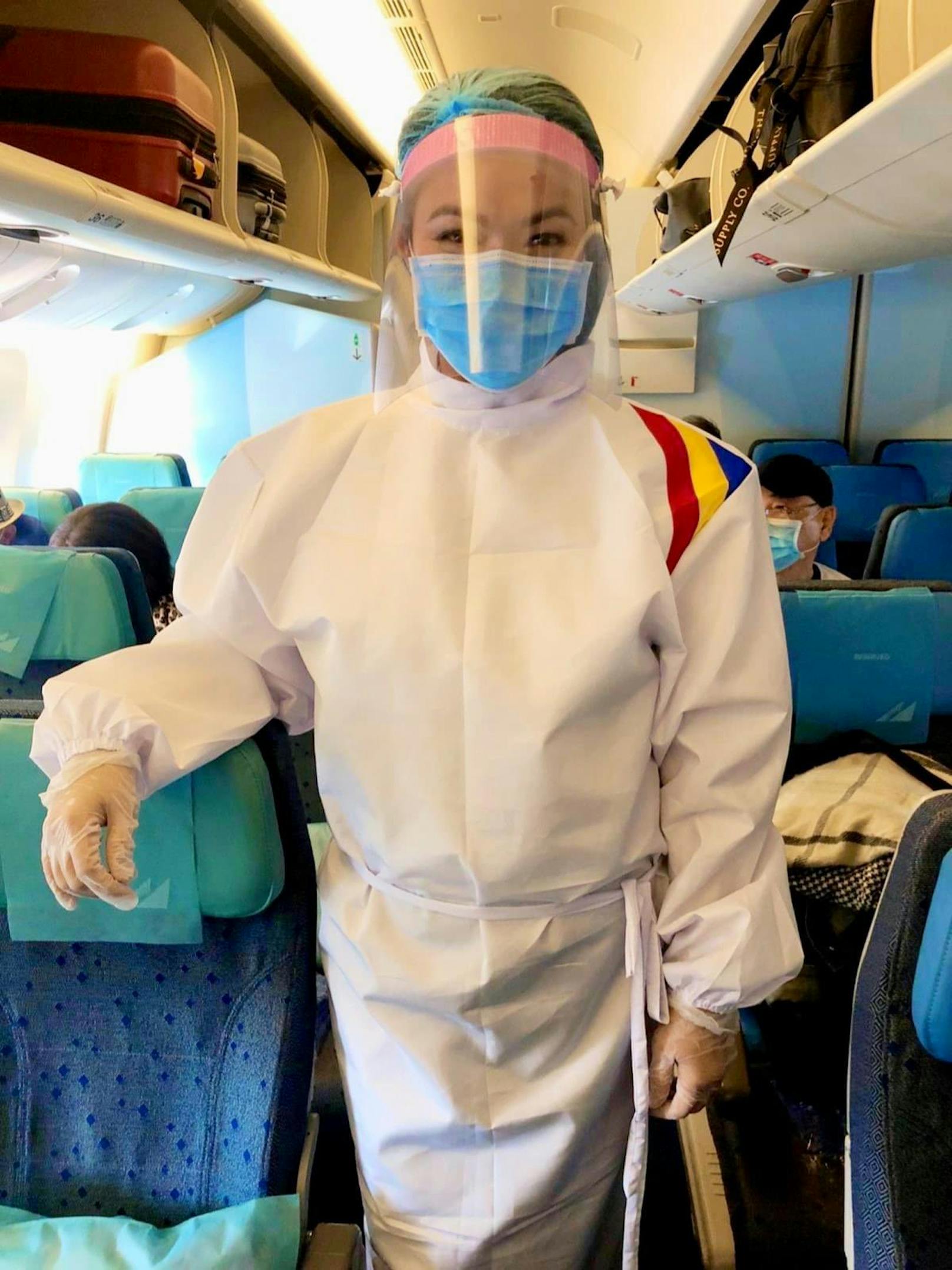 Eine Flugbegleiterin bei Philippines Air trägt Schutzanzug, hier mit bunten Streifen.