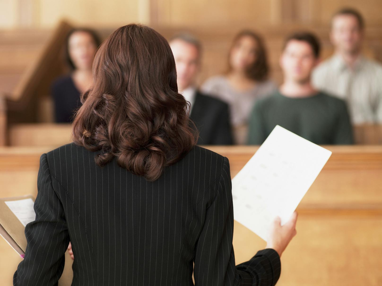 Symbolfoto einer Frau mit Dokumenten vor Gericht.