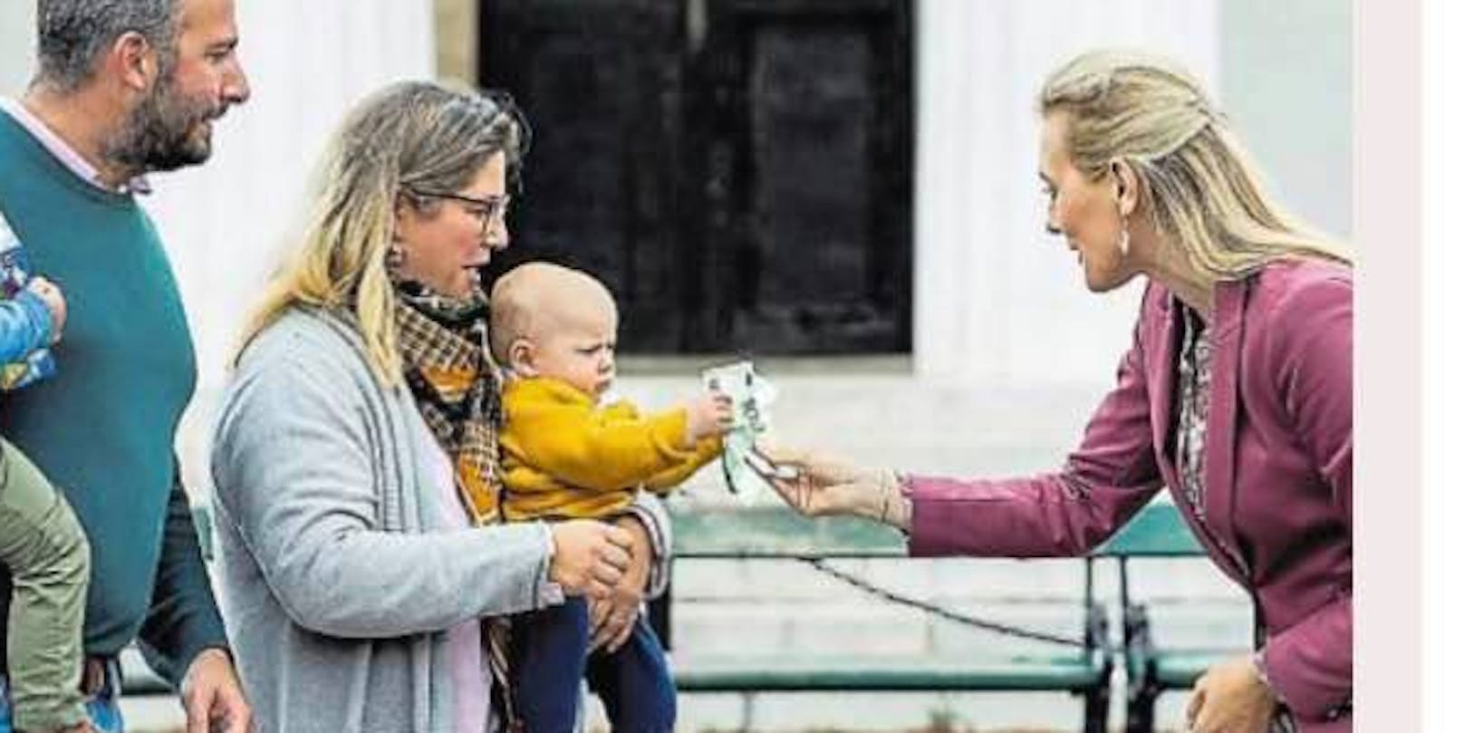 Ministerin Aschbacher inszeniert sich dabei, einem Baby einen 100-Euro-Schein zu überreichen.