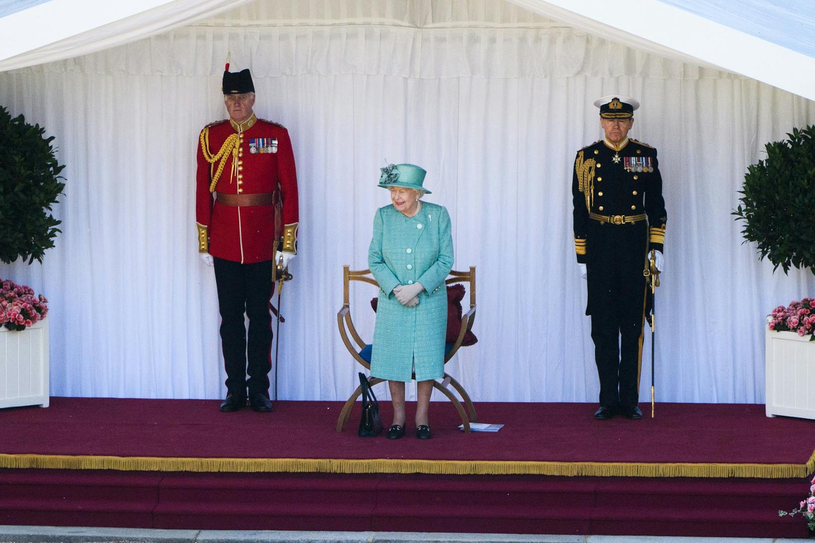 Von einem überdachten Podium aus verfolgte die <strong>Queen</strong> die Parade, flankiert von zwei hochrangigen Militärs. Prinz Philipp blieb der Zeremonie diesmal fern.
