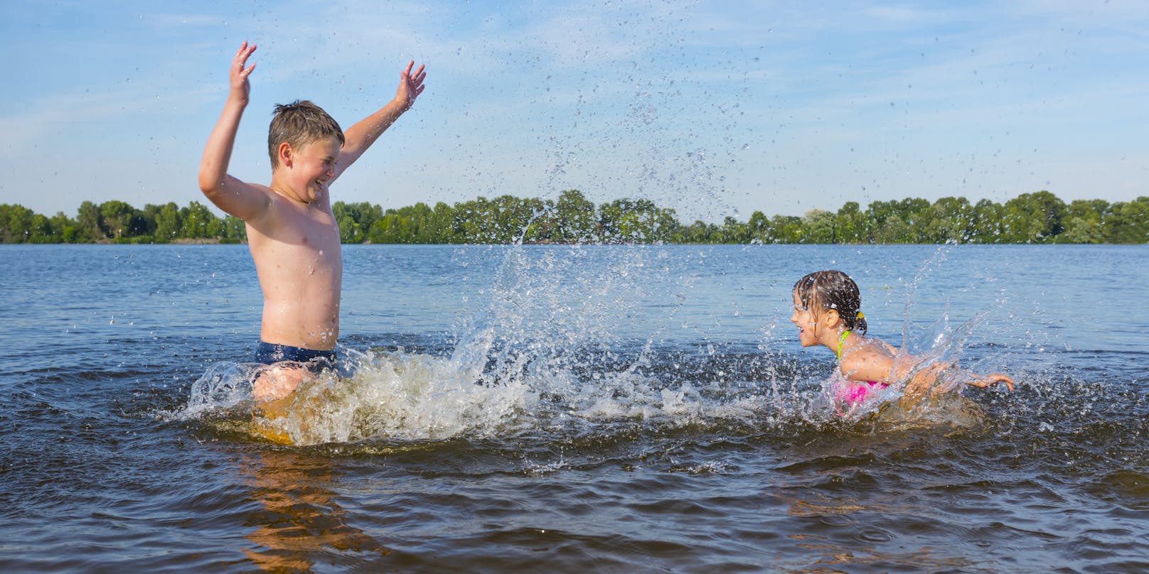 Kinder spielen an einem heißen Sommertag in einem Fluss. Symbolbild