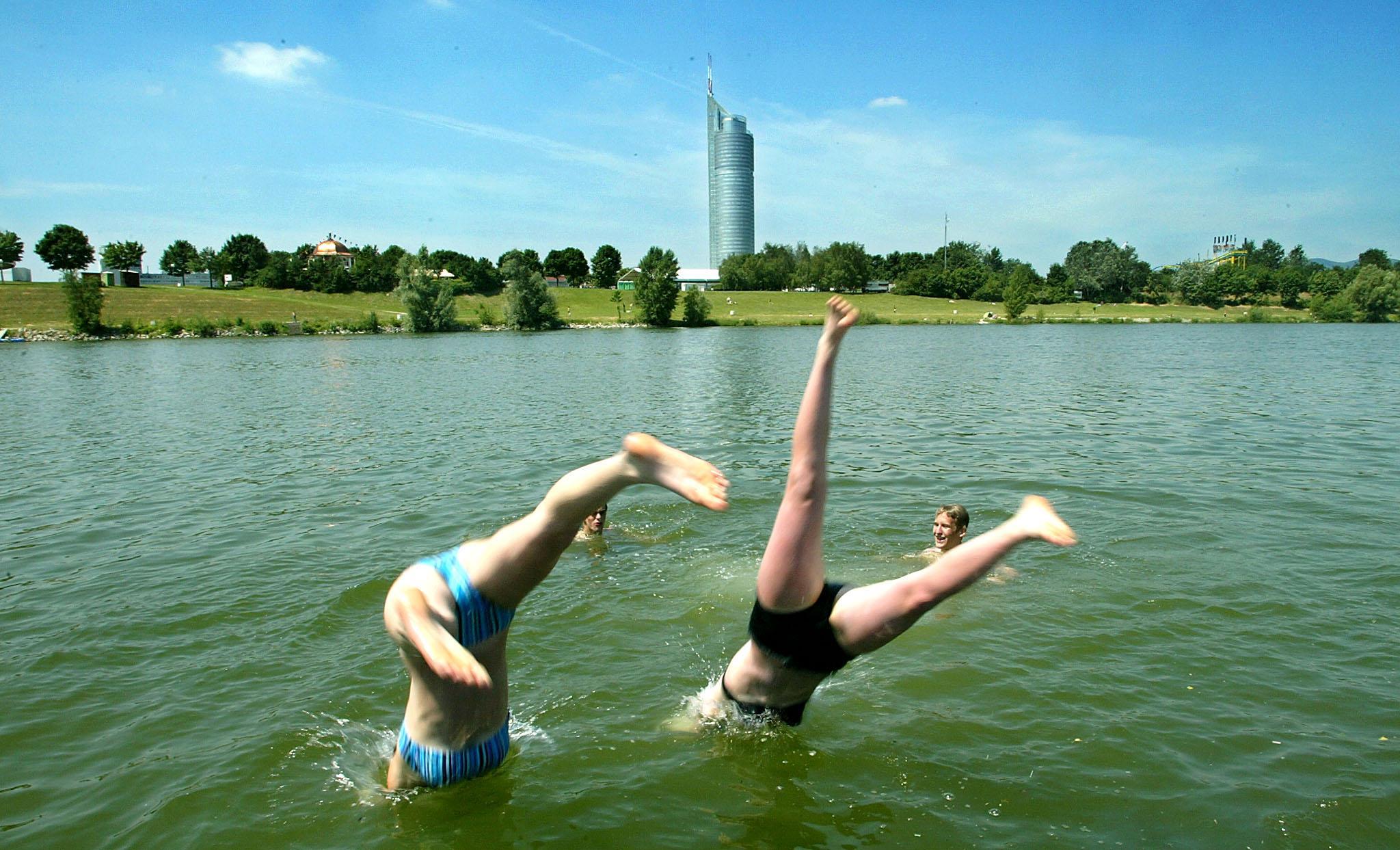 Jugendliche erfrischen sich mit einem Sprung ins kühle Nass der Neuen Donau in Wien