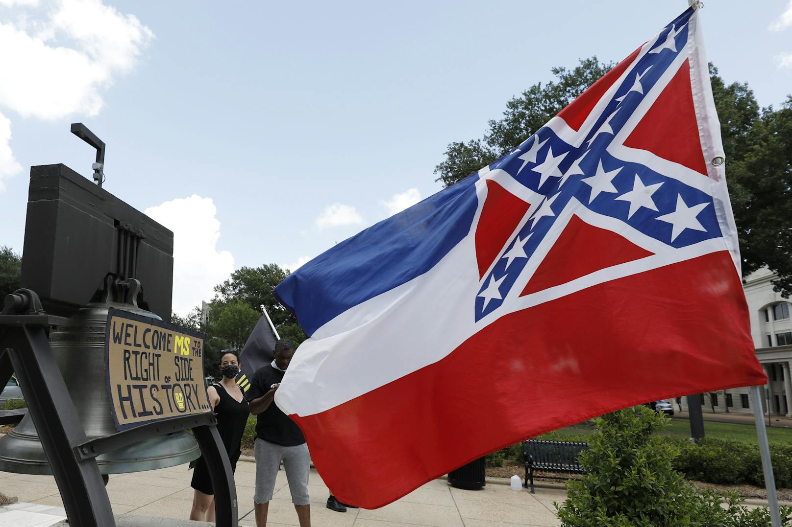 Die bald nicht mehr gültige Flagge des US-Bundesstaats Mississippi neben dem Schild eines Pro-Änderungs-Demonstranten (28. Juni 2020)