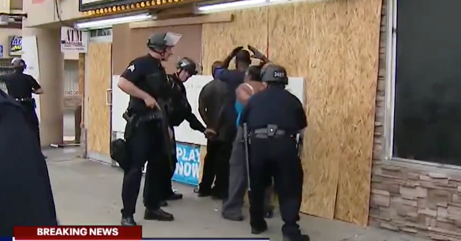 Die herbeigerufene Polizei legt den Beschützern des Ladens Handschellen an, während die Plünderer davonrennen.