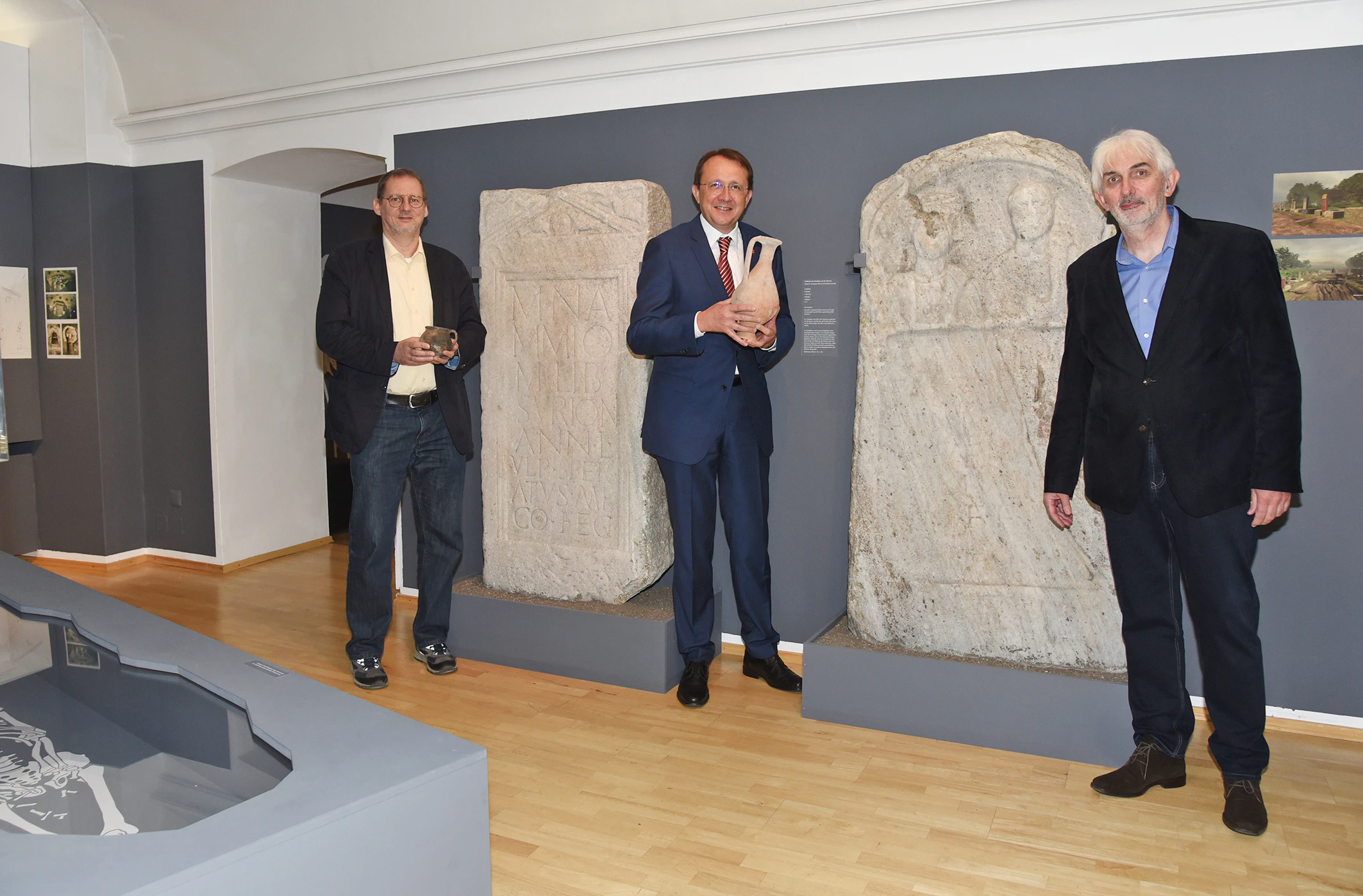 Bürgermeister Matthias Stadler (M.), Stadtmuseumsleiter Thomas Pulle (r.) und Stadtarchäologe Ronald Risy (l.) präsentieren Funde aus den archäologischen Befundungen aus St. Pölten im wieder geöffneten Museum. 