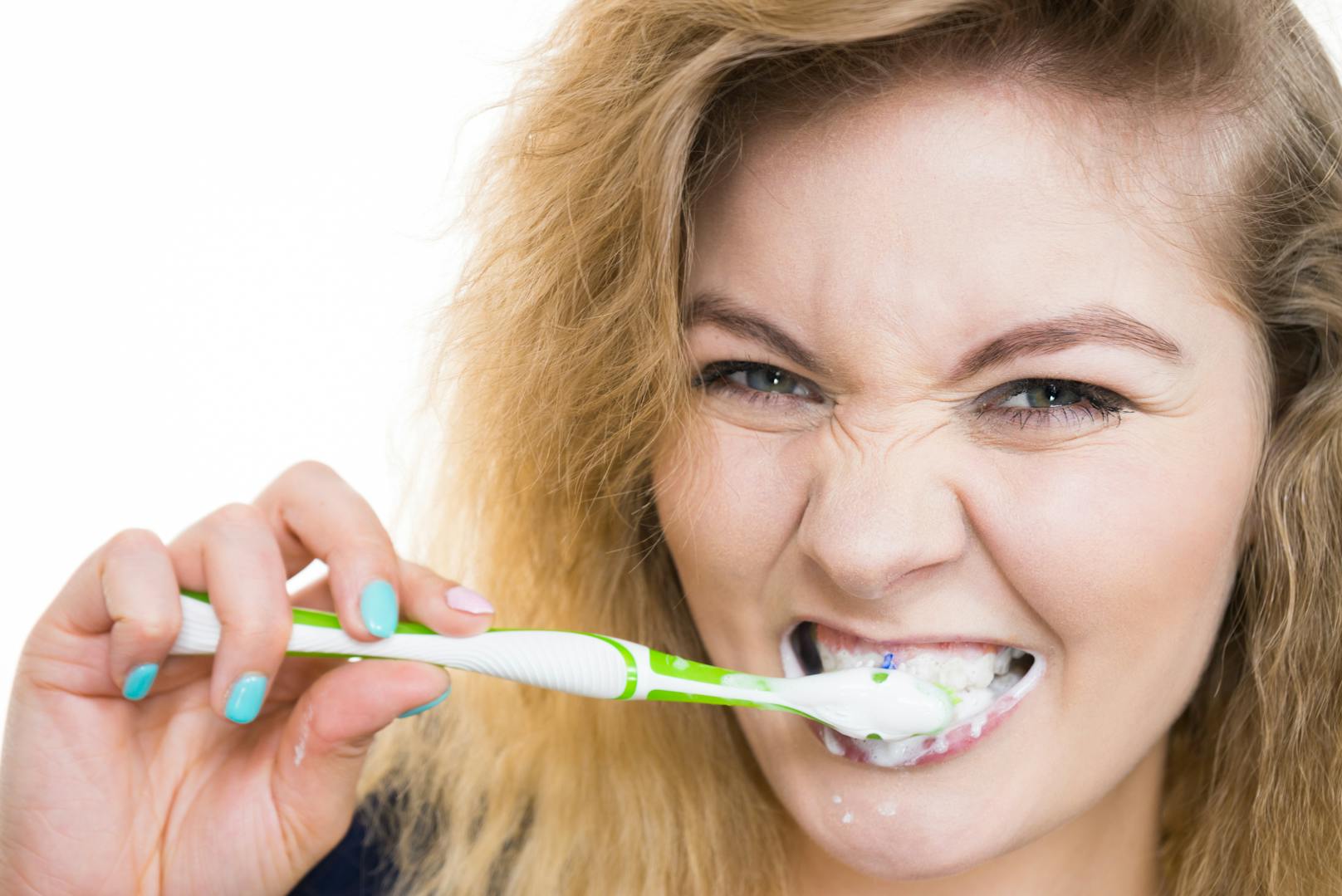 Eine Frau putzt sich energisch die Zähne. Symbolbild