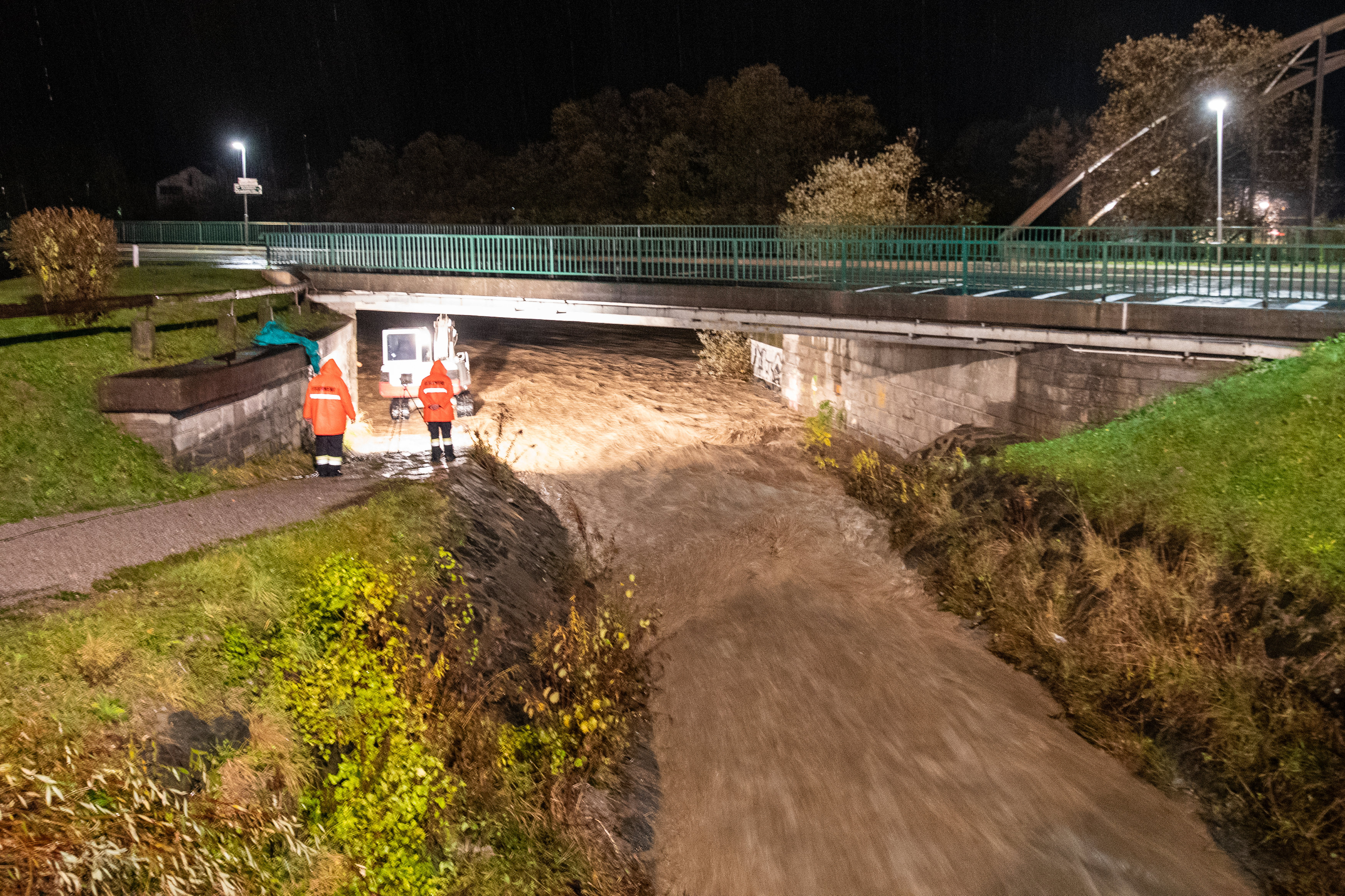 Einsatzkräfte der Feuerwehr und ein Bagger sichern in einer Unwetternacht eine Brücke bei Oberdrauburg. (Archivbild)