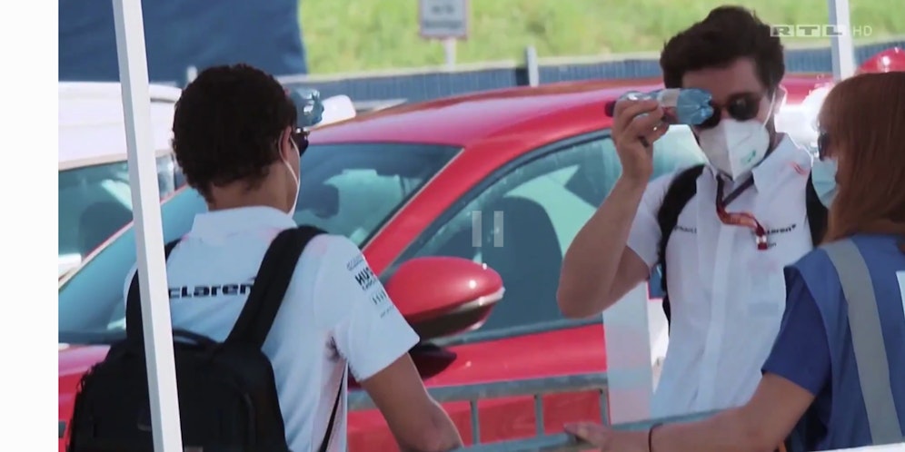 Lando Norris und sein Physio kühlen ihre Stirn mit Wasser.