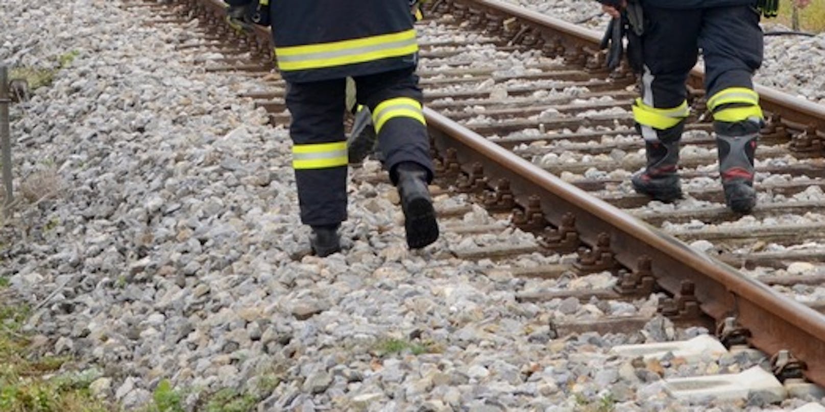 Symbolfoto von Feuerwehrmännern auf einem Gleis.