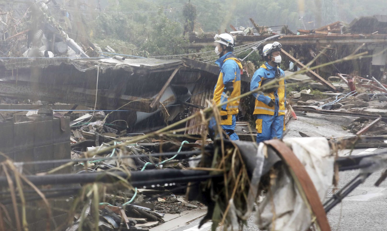 Einsatzkräfte suchen nach Murenabgängen und Überflutungen unter den Trümmern von Häusern nach möglichen Verschütteten. Aufgenommen in Kuma, Präfektur Kumamoto, am 7. Juli 2020