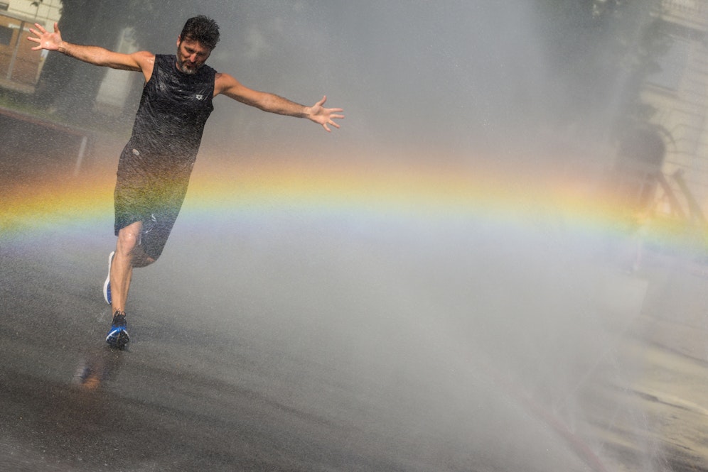 Ein Mann kühlt sich im Sprühnebel am Schwarzenbergplatz. Archivbil