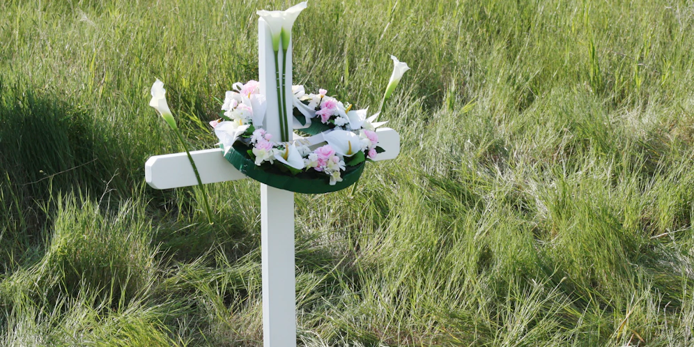 Ein Kreuz mit einem Blumenkranz