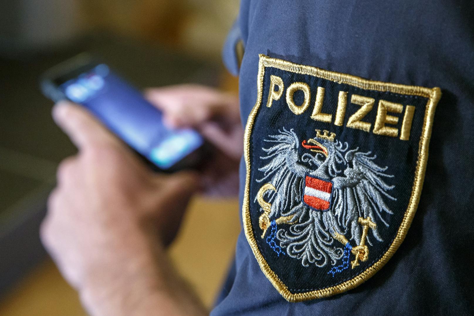Ein Polizist hantiert an seinem Dienstsmartphone. (Symbolbild)