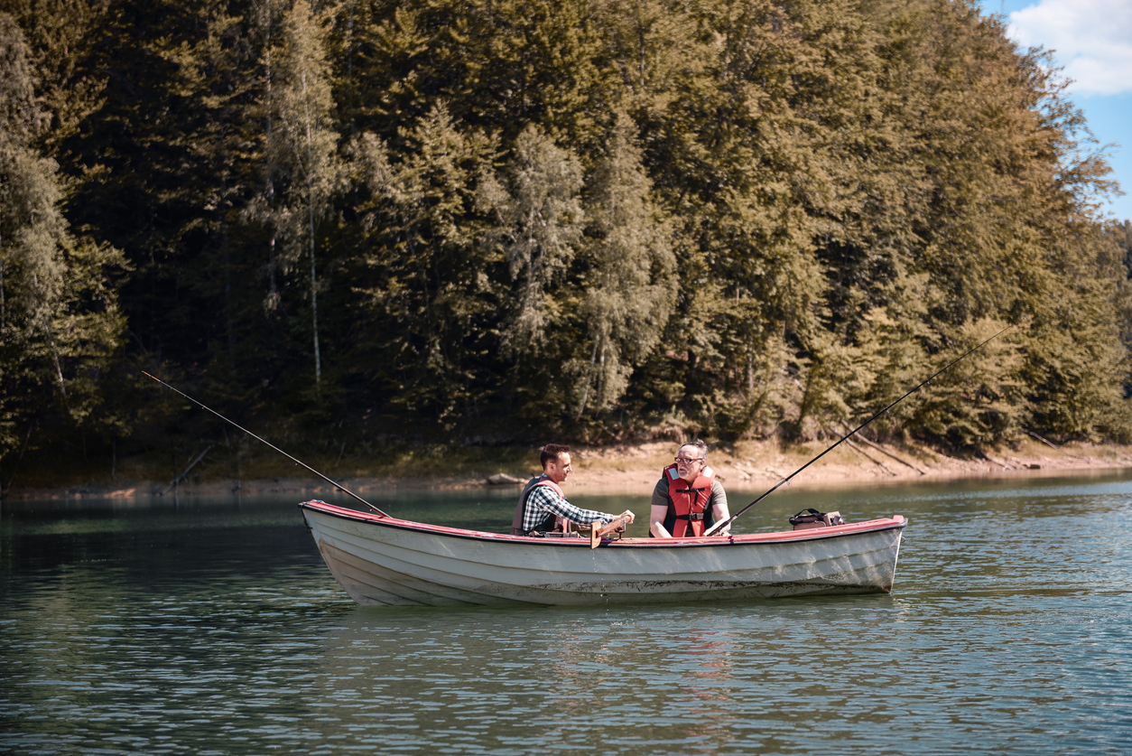 Männer, die in einem ruhigen See vom Boot angeln (Symbolbild)